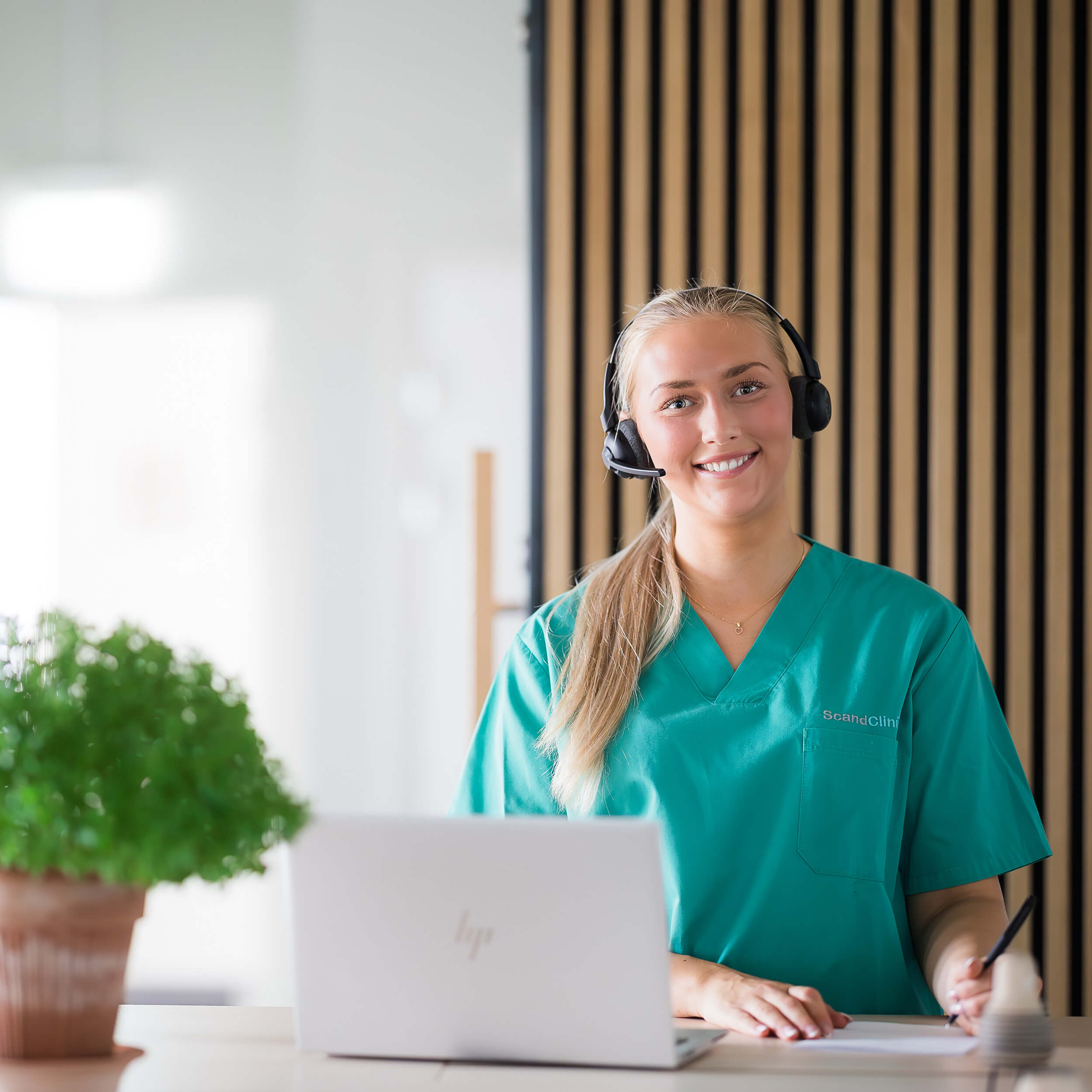 En receptionist med hörlurar ler mot kameran