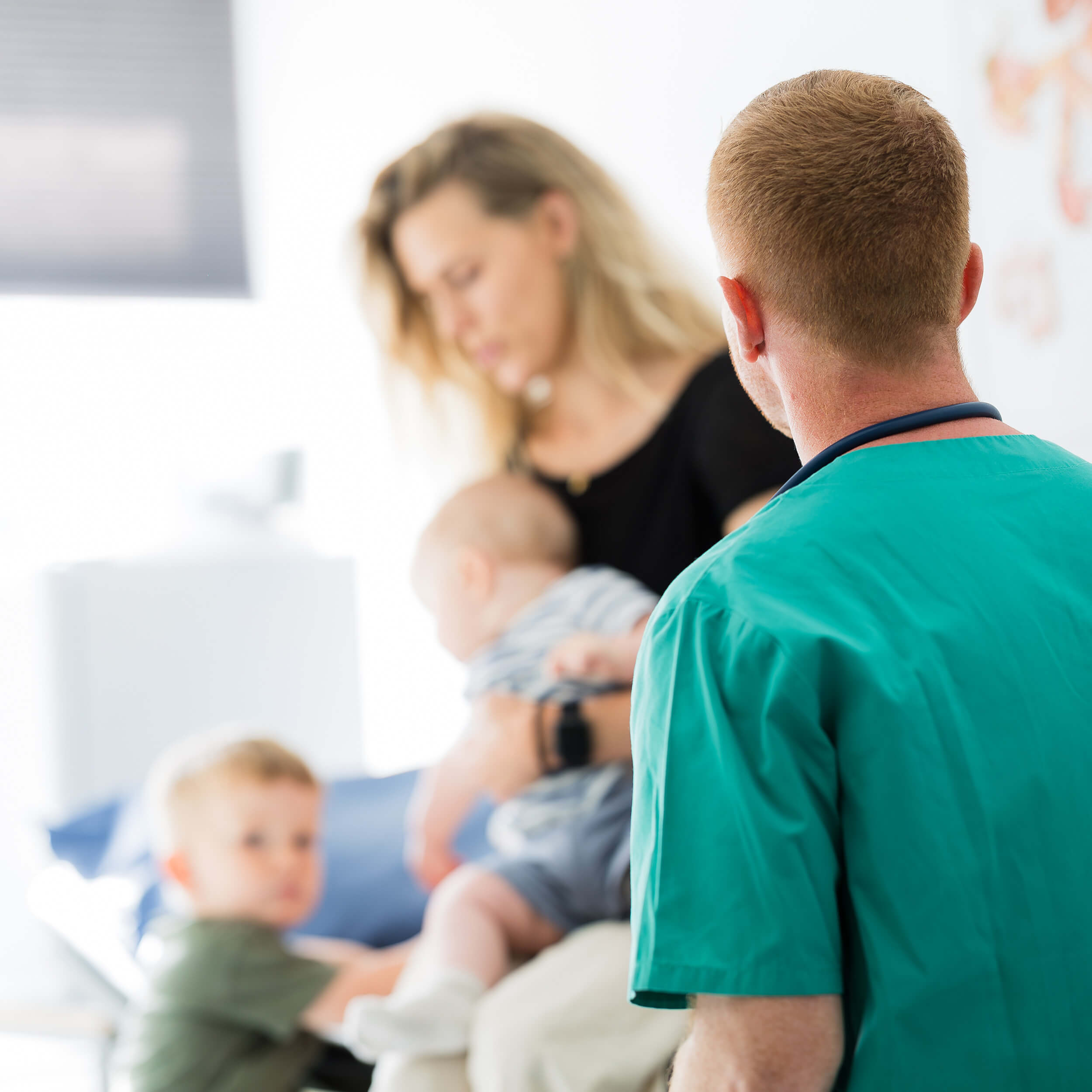 En läkare tar hand om en patient med två små barn